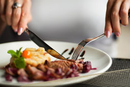 A plate of cooked steak is cut up by a woman